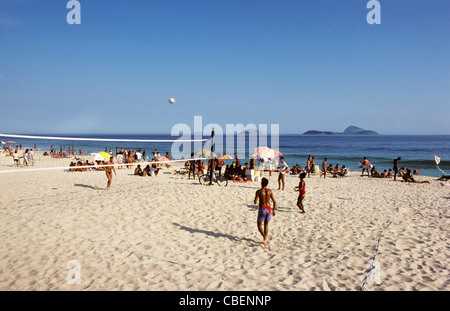 Rio de Janeiro, Brazil. Young people playing volleyball on Copacabana beach with sunhades behind. Stock Photo