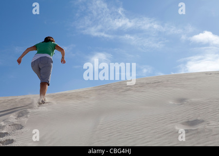 A woman running up the sand dunes at the Nilgen Nature Reserve, Lancelin, Western Australia Stock Photo