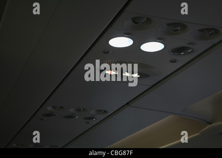 Illuminated signs on roof of a plane, fasten seat belt sign and no smoking sign Stock Photo