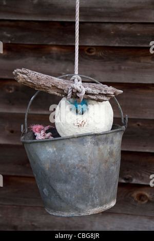 A bucket hanging from a rope tied to a buoy and piece of driftwood Stock Photo