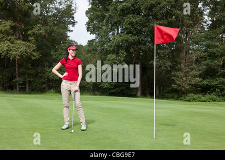 A female golfer standing on a putting green Stock Photo