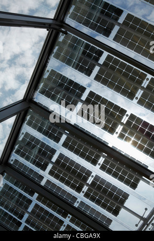 Under a row of solar panels on an open roof with sky in background Stock Photo
