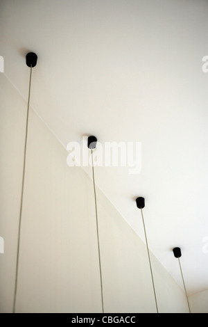 Four light fixtures with cables hanging down from ceiling Stock Photo