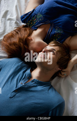 A young couple lying head to head on a bed Stock Photo