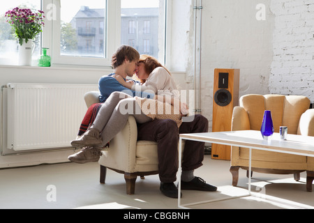 A young woman sitting on her boyfriend's lap, kissing Stock Photo