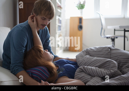 A young couple lying in bed talking and being affectionate Stock Photo