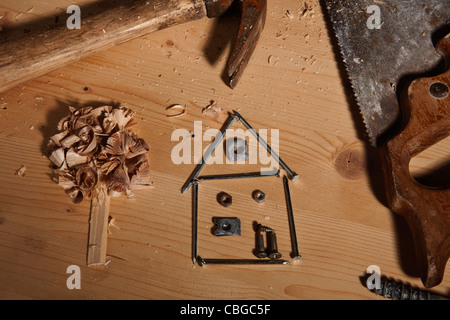 Work tools surrounding a house made of nails and tree made of wood shavings Stock Photo