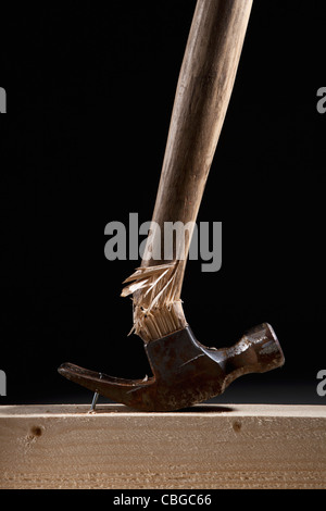 A hammer handle breaking while trying to remove a nail from a beam Stock Photo