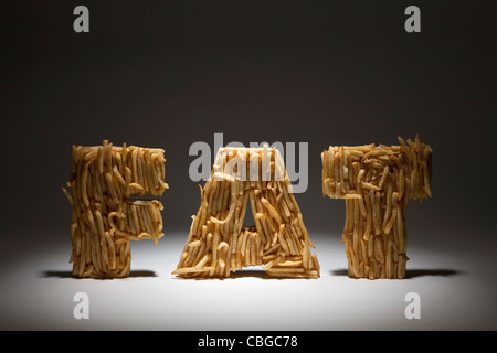 French fries molded to make the word FAT, spot lit Stock Photo