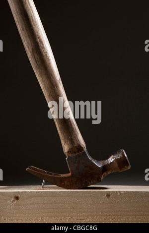 A hammer removing a nail from a wood beam Stock Photo