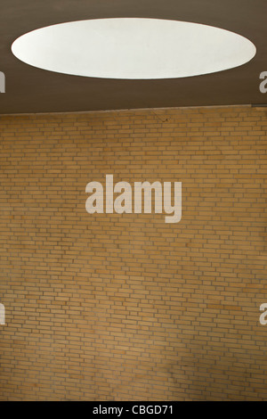 Oval light on ceiling over blank brick wall Stock Photo