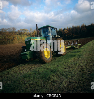 John Deere tractor and coulter plough ploughing grassland to replant in autumn. Stock Photo