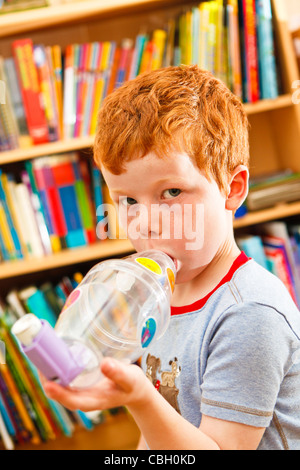 Young boy, aged 7, using an inhaler to combat asthma. Self medicating. Stock Photo