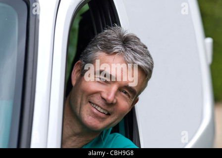 Smiling man in a white delivery van ( L/H drive version) Stock Photo