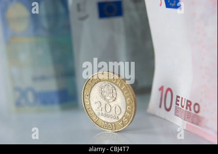 Old portuguese Escudo coin next to Euro bills Stock Photo