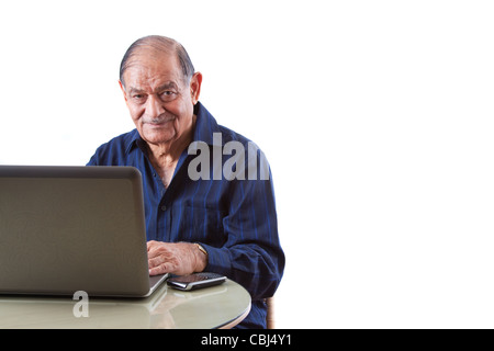 Portrait of a smiling elderly East Indian businessman on his computer laptop Stock Photo