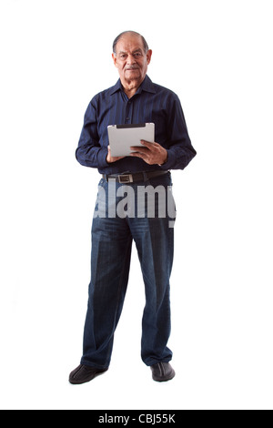 Portrait of a smiling elderly East Indian businessman using an iPad digital tablet Stock Photo