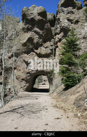 tunnel through a rock outcrop for a single lane dirt road Stock Photo