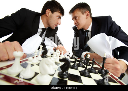 Two men with papers looking at each other aggressively while playing chess Stock Photo