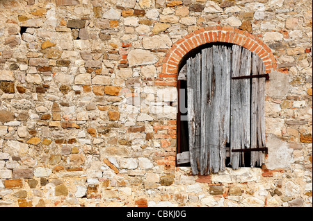 Rustic wall and decaying window shutter, of an old farm house in Tuscany, Italy Stock Photo