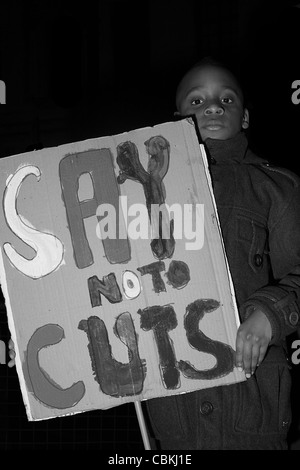 Young black boy holds a placard that reads 'Say no to cuts'. Stock Photo