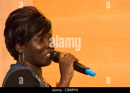 Afro Caribbean woman talking publicly at a conference for people who care for dependant friends and families, London, UK. Stock Photo