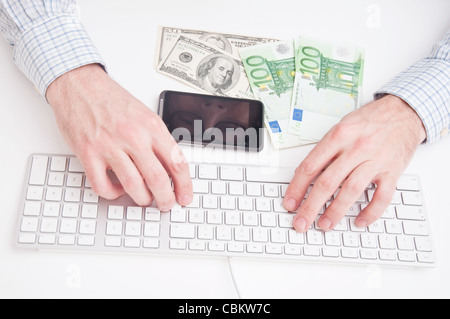 Business man typing at the keyboard, some money on the table and a smart-phone. Eyes of a man reflecting on phone's display. Stock Photo