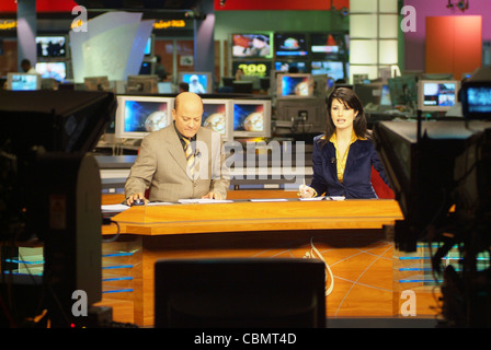 Al Jazeera satellite TV anchors Habib Ghribi and Lina Zahreddine read a news bulletin from studios in Doha, Qatar Stock Photo