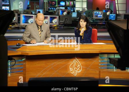 Al Jazeera satellite TV anchors Habib Ghribi and Lina Zahreddine read a news bulletin from studios in Doha, Qatar Stock Photo