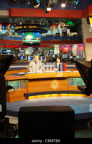 Al Jazeera satellite TV anchors Habib Ghribi and Lina Zahreddine read a news bulletin from studios in Doha, Qatar Stock Photo