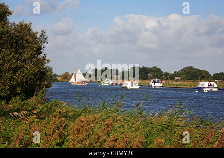 A view of motor cruisers and a yacht tacking on the River Bure near St Benet's Abbey, Norfolk, England, United Kingdom. Stock Photo