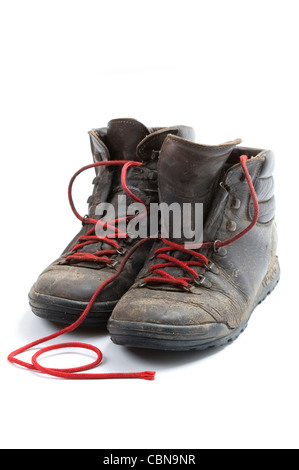 a pair of old, dirty walking boots made of leather with red laces isolated against a white background Stock Photo