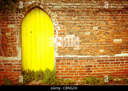 Nice yellow gate in a red brick wall Stock Photo