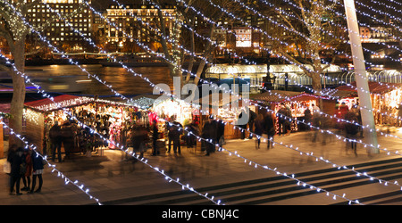 View of the traditional Christmas Market along the South Bank 'Queen's Walk'  London at night looking through Xmas lights Stock Photo