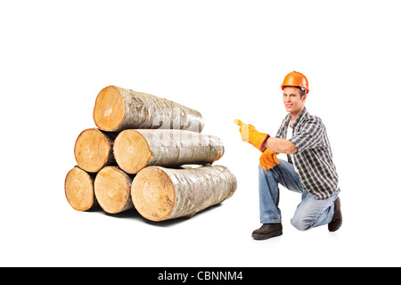 A smiling worker pointing on a pile of beech firewood Stock Photo