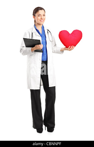 Full length portrait of a female doctor holding a red heart shaped pillow