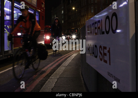 an evening shot of cyclists and traffic passing a 'Waterloo Road' road sign in London, England Stock Photo