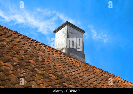 tiled roof top with chimney with blue cloudy sky in background Stock Photo