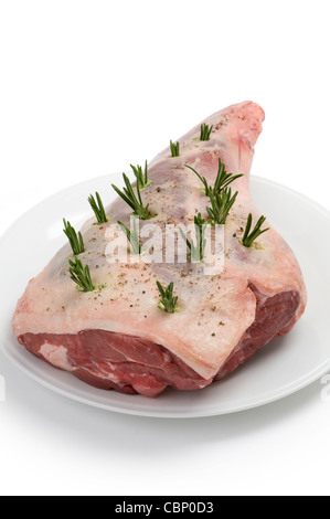 a raw leg of lamb prepared with rosemary for roasting isolated against a white background Stock Photo