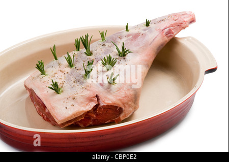 a raw leg of lamb prepared with rosemary for roasting isolated against a white background Stock Photo