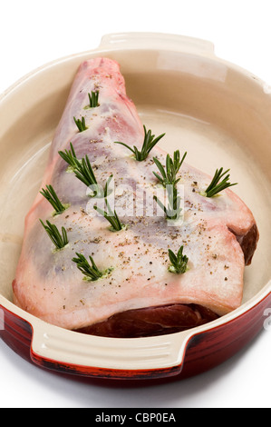 a raw leg of lamb prepared with rosemary for roasting isolated against a white background Stock Photo