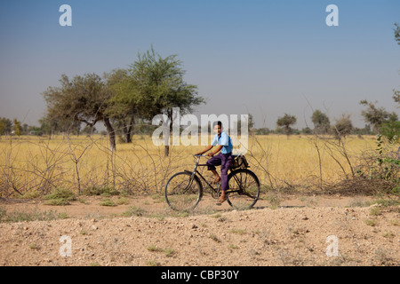 Young Indian Bishnoi boy in school uniform riding bicycle to her school near Rohet in Rajasthan, Northern India Stock Photo