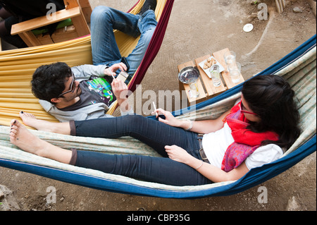 A couple resting on hammocks in Six D.O.G.S. outdoor bar in Monastiraki, Athens, Greece Stock Photo
