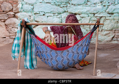 Young Indian woman with her child in hammock at home in Narlai village in Rajasthan, Northern India Stock Photo