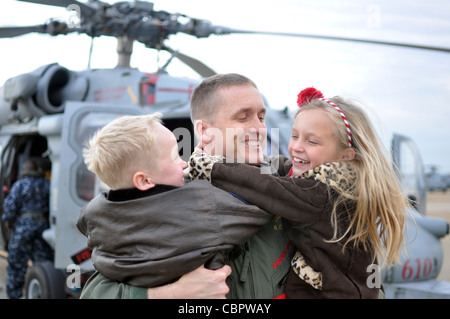 NORFOLK (Dec. 10, 2011) Cmdr. Brian Pummill, the commanding officer of Helicopter Sea Combat Squadron (HSC) 9, hugs his son and daughter during the squadron's homecoming ceremony. HSC-9 completed its first combat deployment embarked aboard the aircraft carrier USS George H.W. Bush (CVN 77) in support of Operations Enduring Freedom and New Dawn. Stock Photo