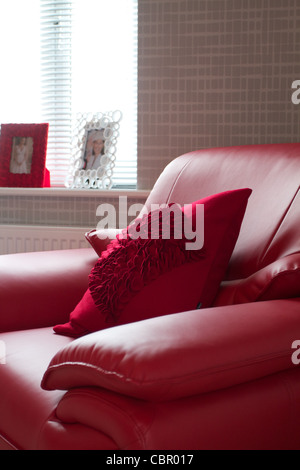 A modern red leather armchair next to a bright window Stock Photo