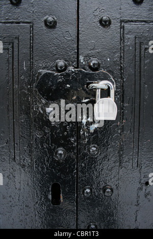 vertical image of padlocked hasp on black painted double doors Stock Photo