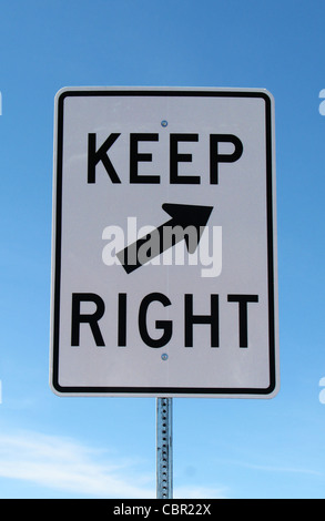 white and black keep right road sign with a blue sky background Stock Photo