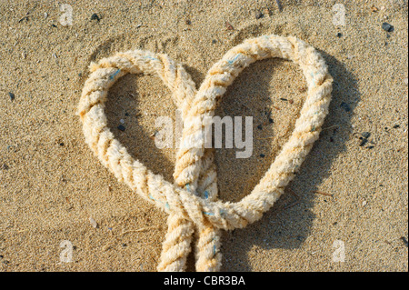 rope with a heart knot - beach sand background Stock Photo