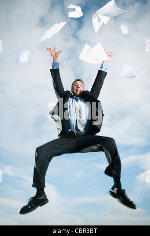 Caucasian businessman jumping in air scattering papers Stock Photo